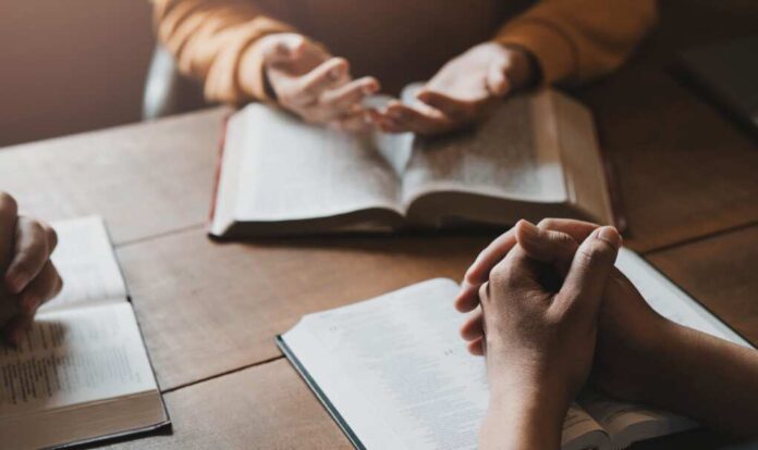 A,Group,Of,Christians,Sit,Together,And,Pray,Around,A