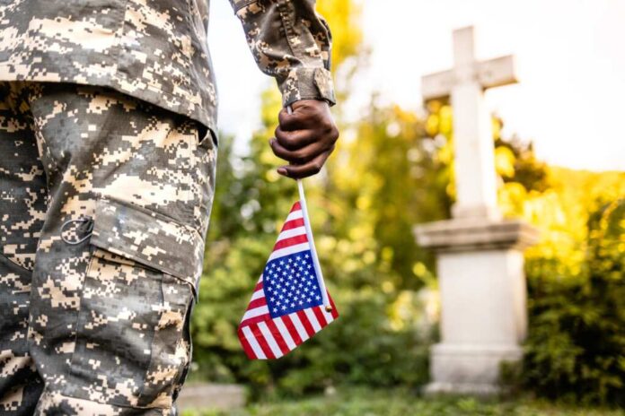 Soldier,In,Uniform,Holding,Usa,Flag,At,Cemetery,In,Honor