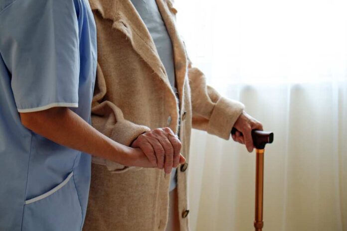 Senior,Woman,Holding,Quad,Cane,Handle,In,Elderly,Care,Facility.
