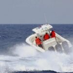 A speedboat with passengers navigating through rough ocean waves