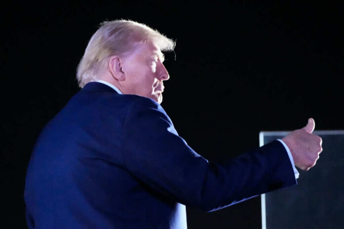 A political figure giving a thumbs up gesture at a night event