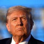 Close-up portrait of a serious-looking political figure outdoors