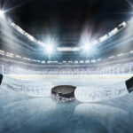 Close-up of a hockey puck on the ice with a hockey stick in the foreground