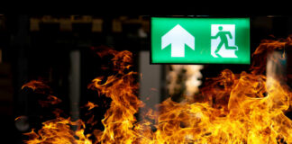 Green emergency exit sign with flames in the foreground
