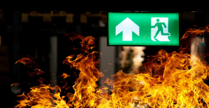 Green emergency exit sign with flames in the foreground
