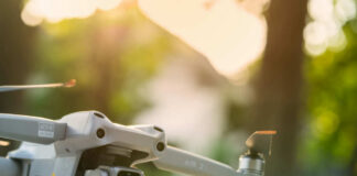 Close-up of a drone with a camera, set against a blurred outdoor background