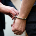A close-up of a person being handcuffed by an officer