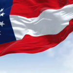 Georgia state flag waving against a blue sky