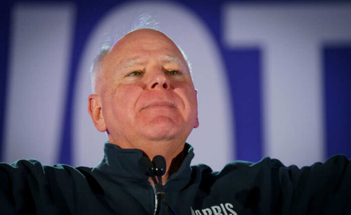 Man in a dark jacket speaking passionately at a podium with a microphone