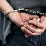 Hands cuffed behind the back, indicating arrest