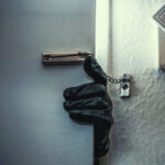 A gloved hand reaching through a partially opened door