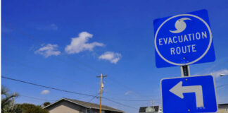 Evacuation route sign with a left turn arrow near residential buildings