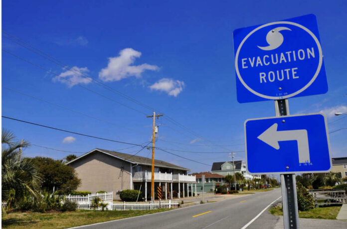 Evacuation route sign with a left turn arrow near residential buildings