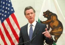 A government official delivering a speech with flags in the background