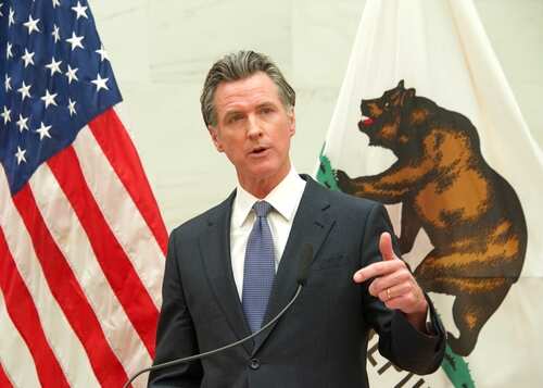 A government official delivering a speech with flags in the background