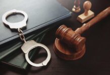 Handcuffs and a gavel on a desk with legal books