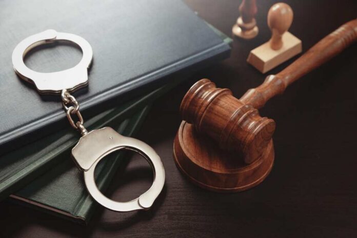 Handcuffs and a gavel on a desk with legal books