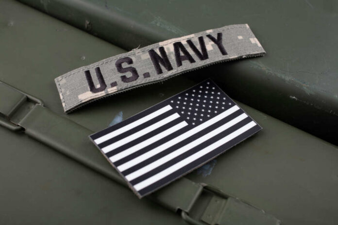 U.S. Navy patch and American flag on a green surface