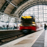 A busy train station with commuters and a train in motion