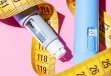 An insulin pen and measuring tape on a pink background