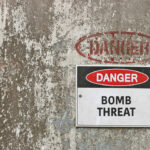 Warning sign indicating a bomb threat on a weathered wall