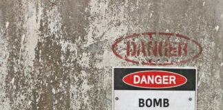 Warning sign indicating a bomb threat on a weathered wall