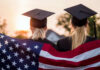 Immigration Clash: California’s Graduation Gamble Two graduates wearing caps holding an American flag during sunset