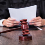 A judge holding documents with a gavel in the foreground