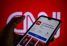 Viral CNN Clash: Media Vs. Misleading Politics A hand holding a smartphone displaying the CNN news app against a red background