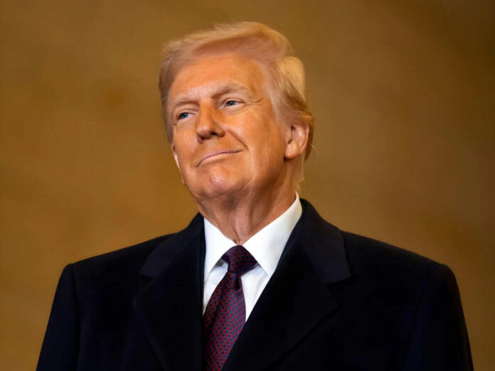 A man in formal attire smiling confidently against a neutral background