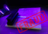 A passport under UV light with a stamp indicating fraud