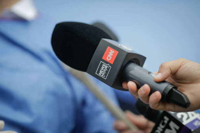 shutterstock_1978216091.jpg A hand holding a CNN microphone during a news interview