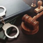 Handcuffs and a gavel on a desk with legal books