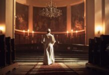 Trump’s Iran War Sparks Catholic Outrage A religious figure standing in a church with candlelight and historic artwork
