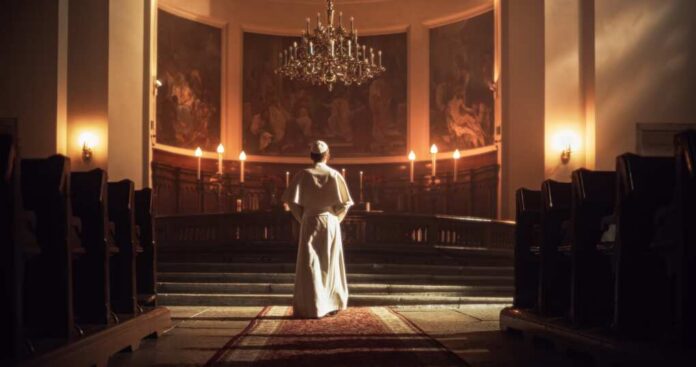 shutterstock_2253549795.jpg A religious figure standing in a church with candlelight and historic artwork