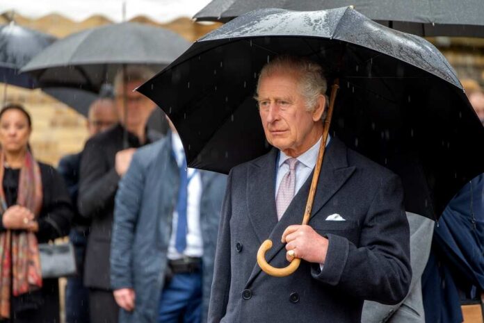 A man in formal attire holding an umbrella in the rain