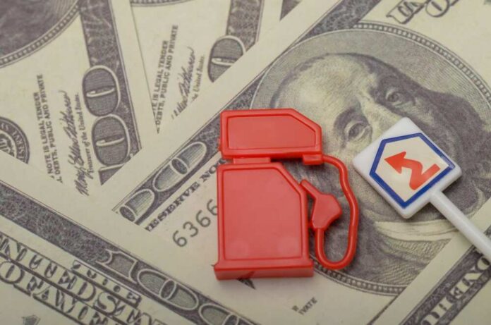 shutterstock_2553882425.jpg Red fuel pump toy next to hundred dollar bills