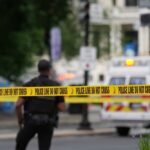 Police officers near a crime scene marked by caution tape