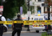 Police officers near a crime scene marked by caution tape