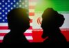 Silhouettes of two figures against the backgrounds of the American and Iranian flags