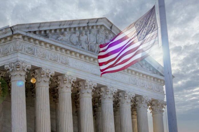 The Supreme Court building with an American flag waving in front