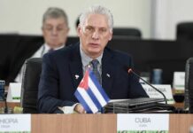 Cuban official speaking at a conference with a flag in front