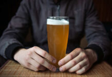 Person holding a glass of craft beer in a bar