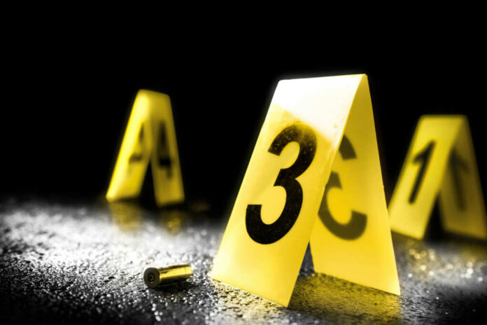 shutterstock_733909831.jpg Yellow evidence markers with numbers at a crime scene alongside a bullet casing