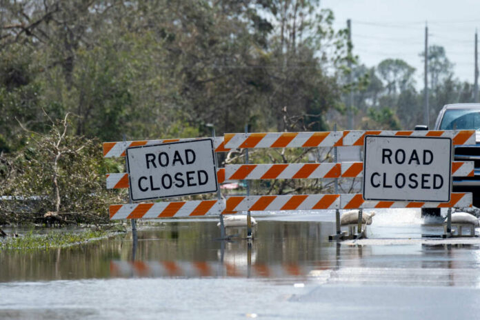shutterstock2349322069jpg Flooded road with road closure signs and traffic barriers
