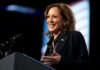 A woman smiling while speaking at a podium with a microphone