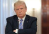 A serious-looking man in a suit with arms crossed during a meeting