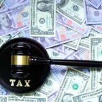 Massive Wealth Drain: Tax Proposal Costs Billions A gavel with the word 'TAX' on it placed on a background of US dollar bills