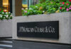 Sign of JPMorgan Chase & Co. in front of a corporate building with flowers