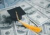 A graduation cap placed on a pile of hundred dollar bills